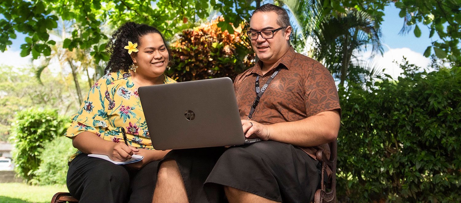 Samoan Man and Woman on computer outside in the sun